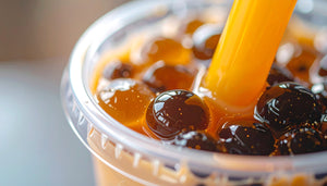 Close-up of a bubble tea with a straw in a clear plastic cup.
